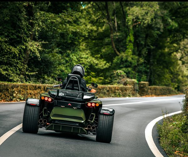 Grünes rewaco Trike in einer Kurve, von hinten